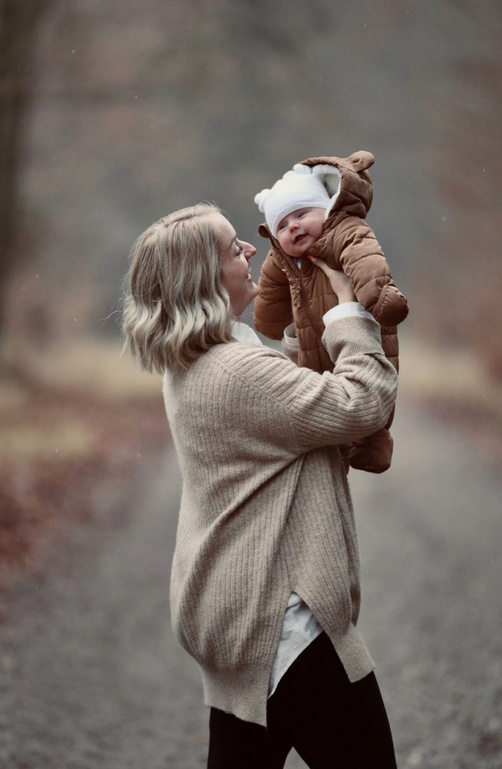 Mutter hebt ihr Baby im Herbst in die Luft