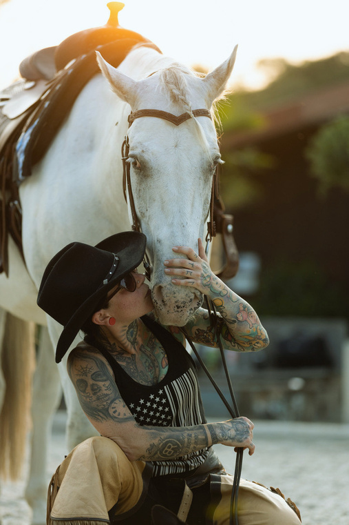 Reiterin mit Cowboyhut küsst ihr weißes Pferd