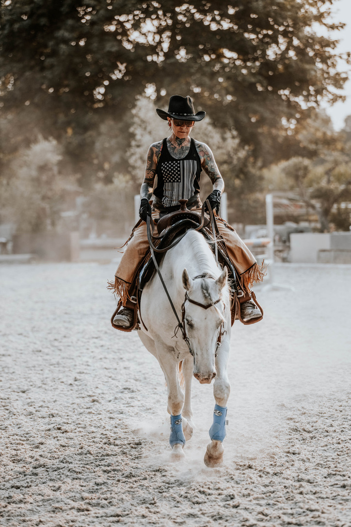 Reiterin mit Cowboyhut auf einem weißen Pferd in der Reithalle